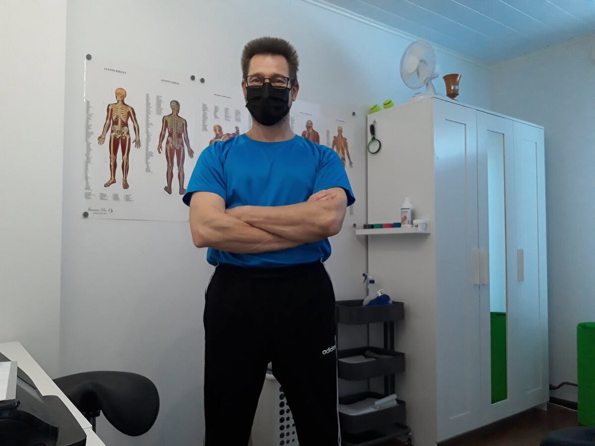Anssi Aronen seisoo vastaanottotilassa lihaskarttojen edessä.